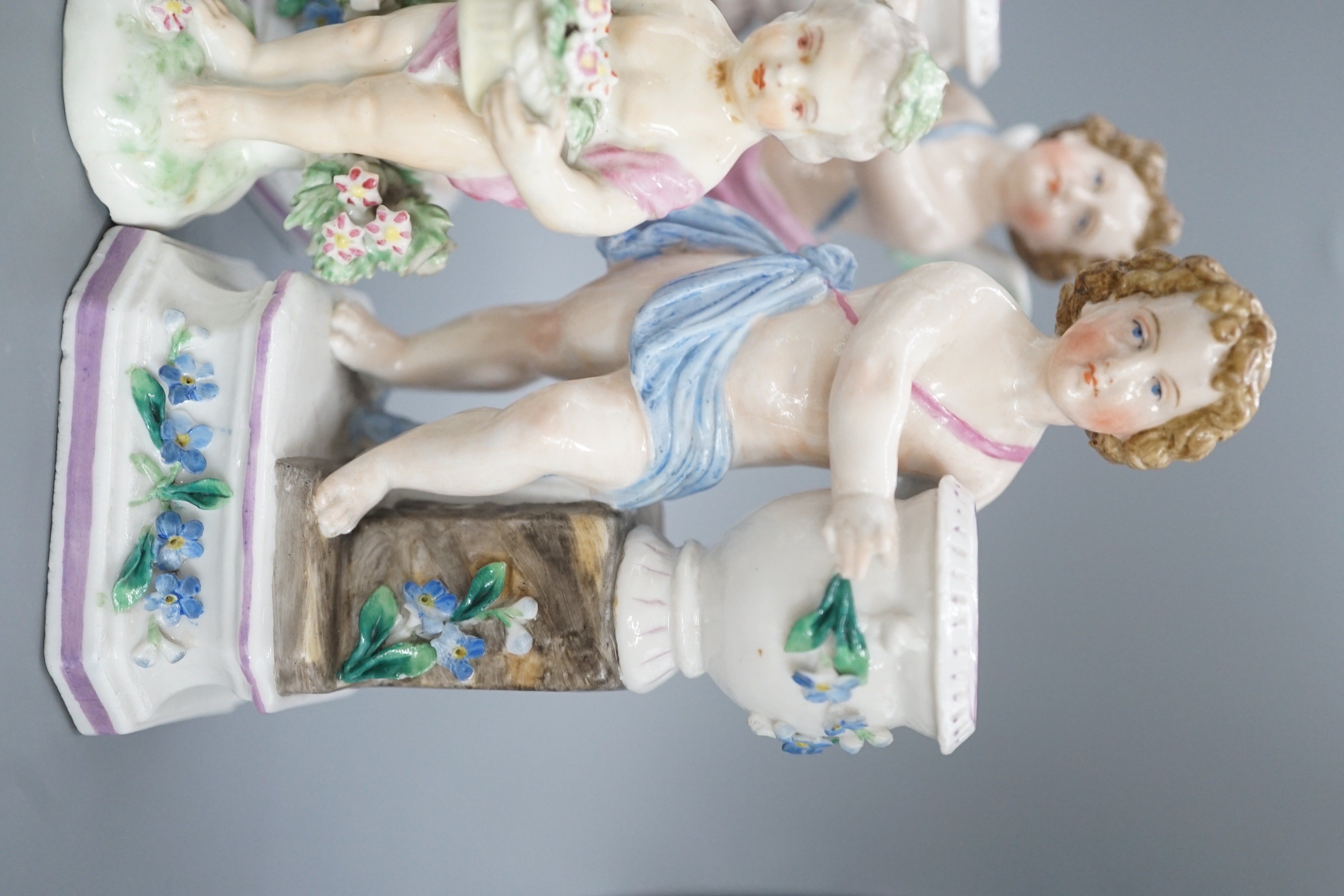 A pair of Continental porcelain cherub candlesticks, 13.5cm, a figural bonbon and a Derby figure